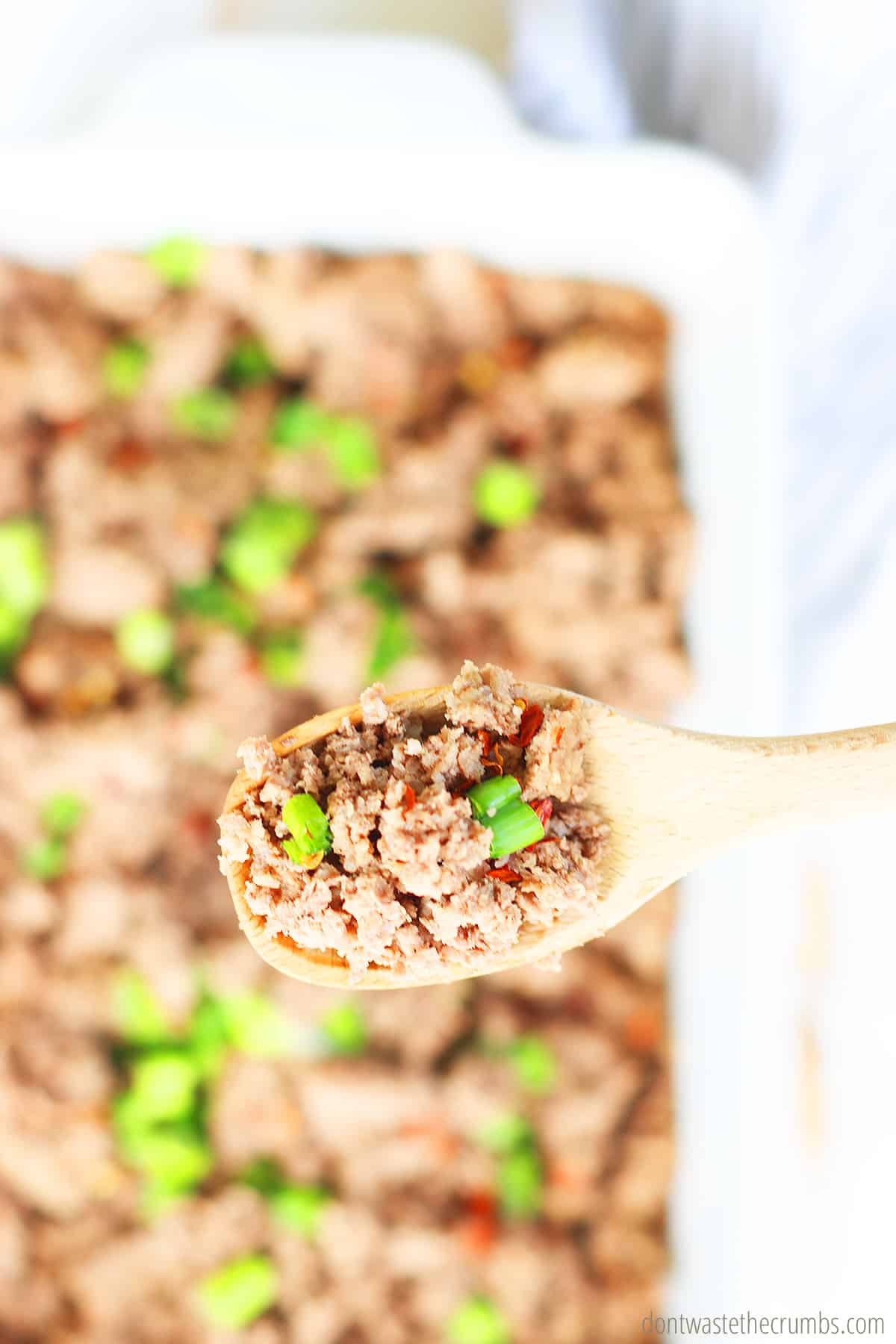 A wooden spoon full of freshly cooked ground beef in the Instant Pot. 