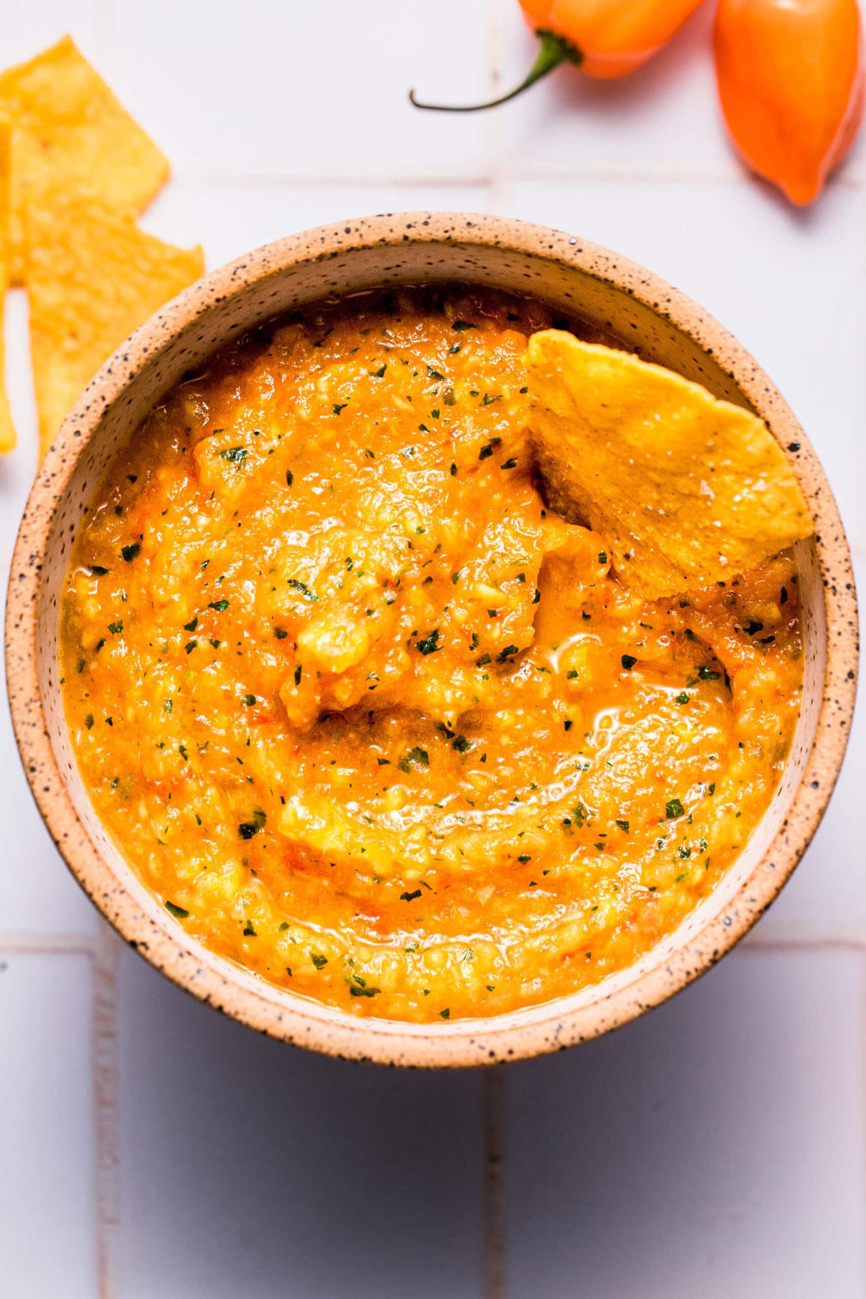 Corn chip dipping into bowl of habanero mango salsa.