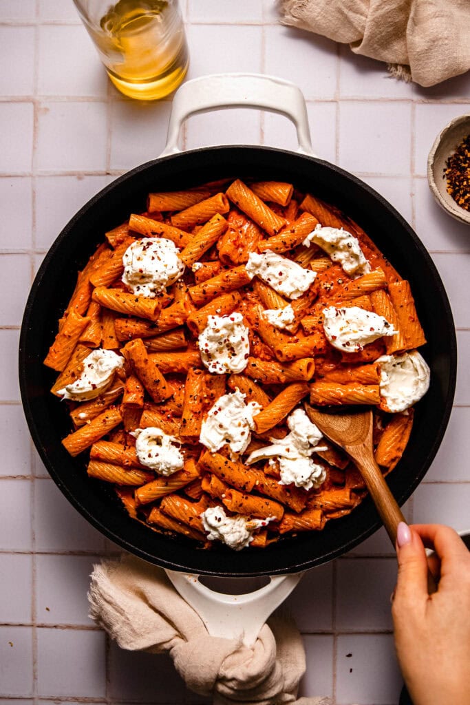 Tomato pasta in skillet topped with dollops of burrata cheese.