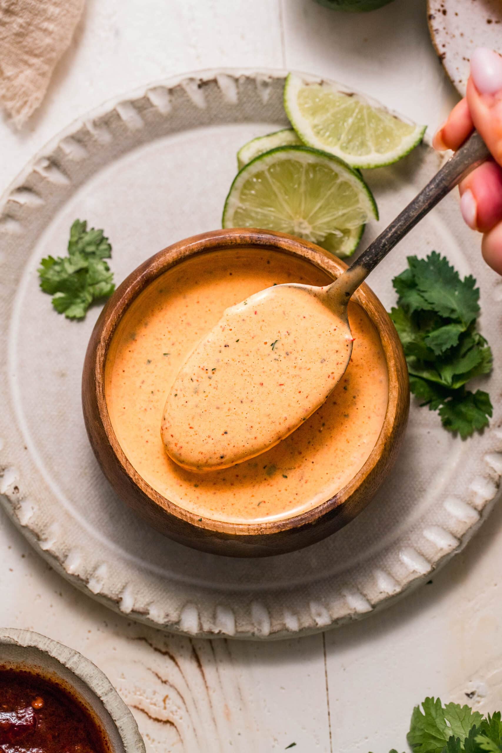 Overhead shot of spoon dipping into small bowl of chipotle ranch sauce.
