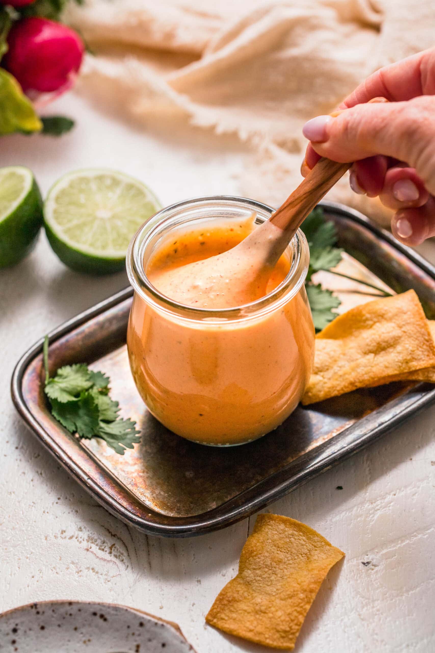 Hand stirring spoon into small jar of southwest ranch dressing.
